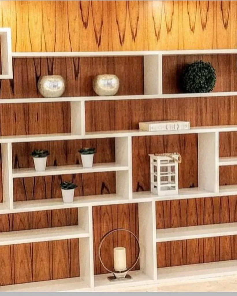 Built-in white shelving wall with warm wood grain backing and decor
