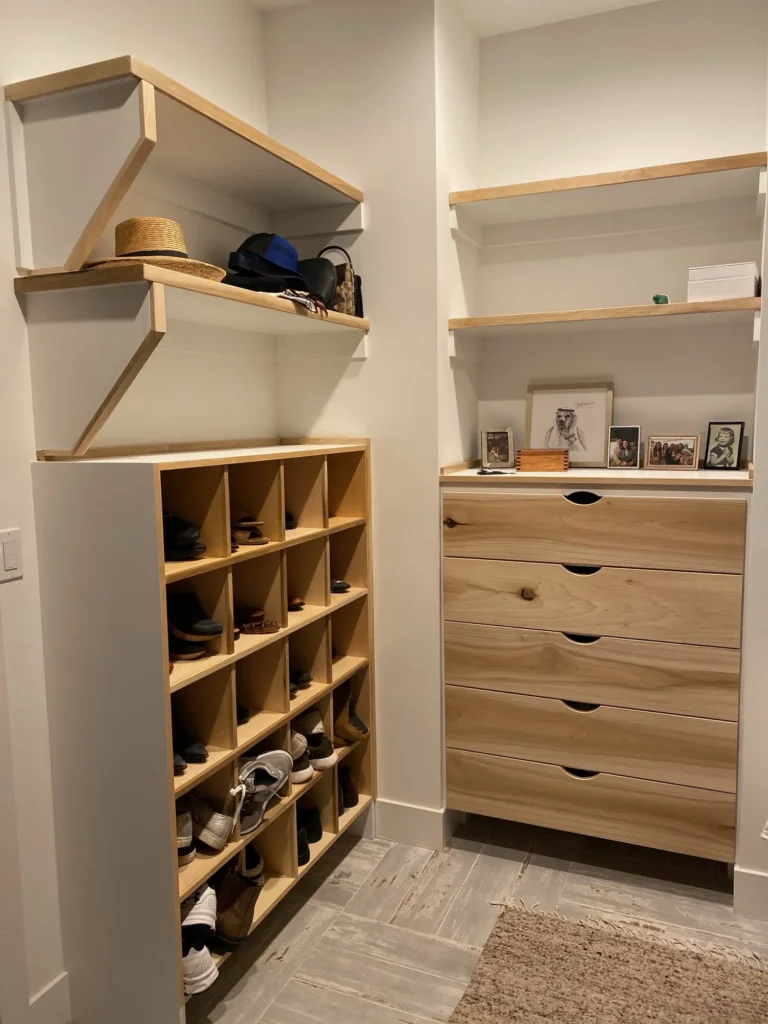 Custom closet with open shoe cubbies, light wood drawers and upper shelves