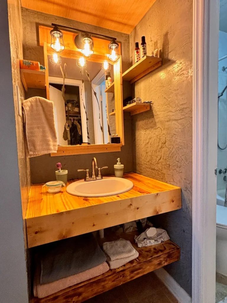 Rustic solid wood bathroom vanity with floating shelves and Edison bulb lighting