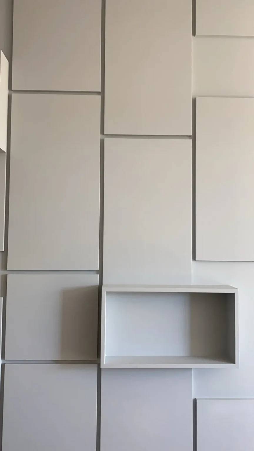 Finished light gray 3D geometric panel wall with a built-in open niche